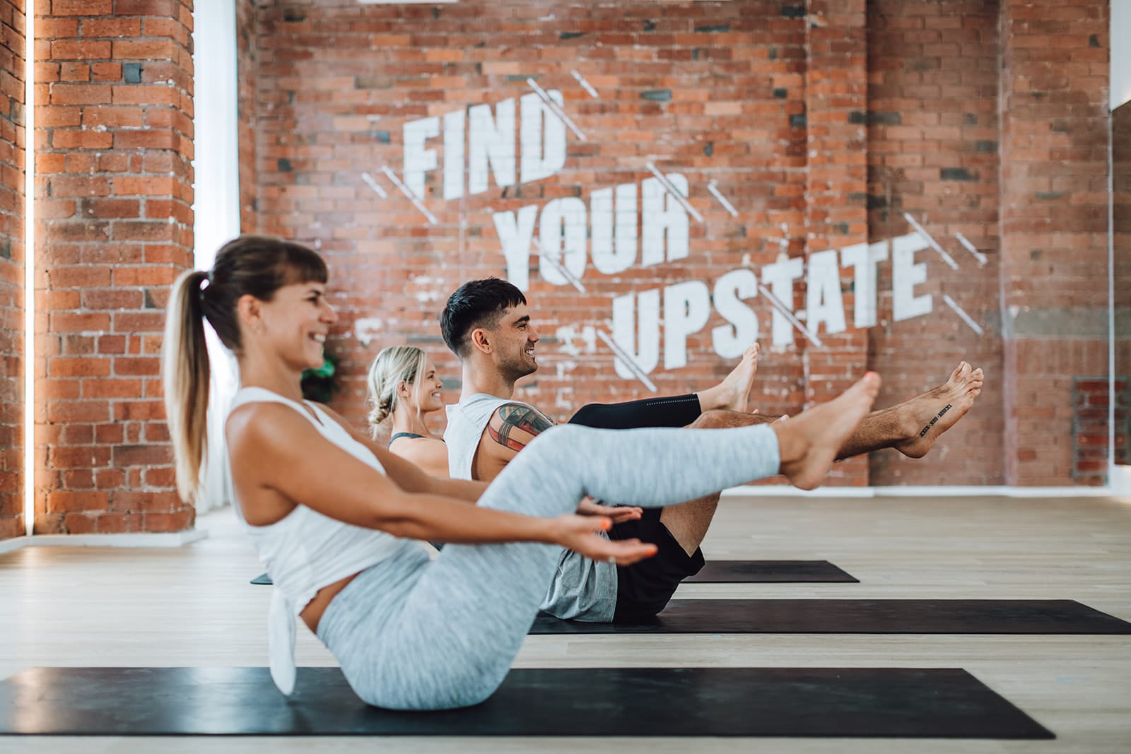 Group of happy people workout in Balaclava hot room. The studio space is made of industrial brick and there is a positive, bright atmosphere in the space.