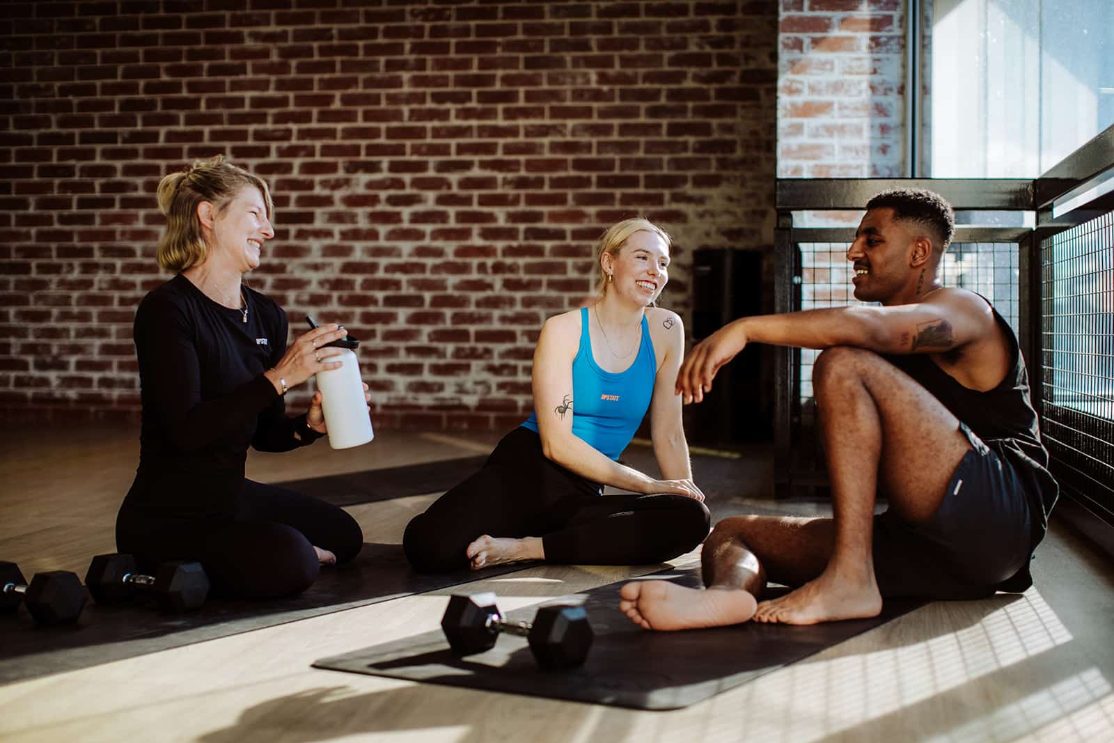Bring a friend free perk. Smiling Upstaters relax in the heated mat room at Fitzroy Studio.